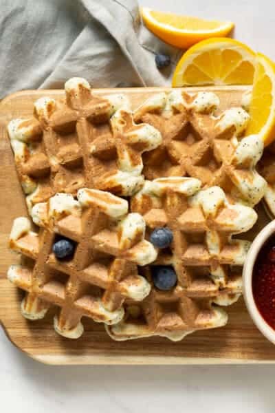 platter of orange poppyseed protein waffles with a bowl of strawberry sauce